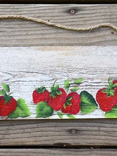 a wooden sign with strawberries painted on the front and back of it, hanging from a rope