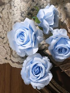 three blue roses sitting on top of a lace doily