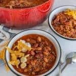 three bowls filled with chili and other food