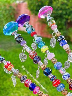 a wind chime with lots of colorful beads hanging from it's side in the grass