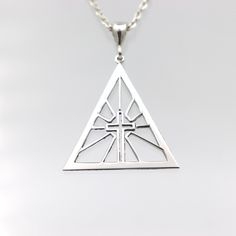 This Cross 925 Silver Necklace features a striking design enclosed within a triangle frame, symbolizing strength and unity. Crafted from high-quality 925 sterling silver, this necklace combines timeless elegance with spiritual significance. Its geometric frame enhances the cross's powerful symbolism, making it a meaningful accessory for those who cherish their faith. Material: 925 Sterling Silver Pendant Diameter: 2.8 cm - 1.1 inches Chain Lengths Available: 40 cm (15.75 inches), 45 cm (17.72 in Sterling Silver Pyramid Jewelry As Gift, Pyramid-shaped Sterling Silver Jewelry Gifts, Sterling Silver Pyramid Jewelry For Gifts, Nickel-free Triangle Sterling Silver Jewelry, Triangle Shaped Sterling Silver Jewelry For Anniversary, Balance Symbol, Triangle Frame, Symbol Jewelry, Geometric Frame