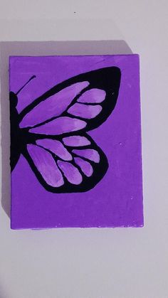 a purple square with a black butterfly on it's back and white wings painted on the side