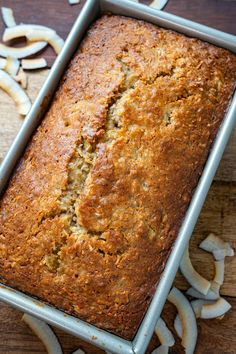 a loaf of banana bread sitting on top of a wooden table next to sliced bananas