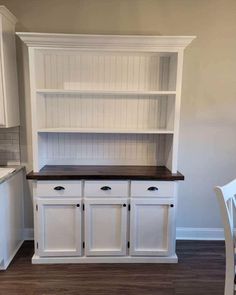 an empty kitchen with white cabinets and wood floors