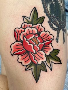 a woman's thigh with a flower tattoo design on the leg and an insect sitting on top of it