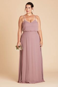 a woman in a long purple dress is standing with her hands on her hips and looking at the camera