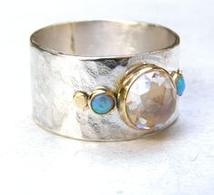 Recycled Silver and 14k Yellow Gold with Lovely White Topaz ring and blue opals MADE TO ORDER You are looking at a beautiful HAND MADE silver and White Topaz and blue opals ring . The stones are setting in 14k gold bazel. It is impressive, powerful and very beautiful ring. Size white topaz stone: 8mm Size blue opals sre 3mm Silver width: 10mm Custom rings are available. Convo me for information. Fallow me on facebook for newest updates. http://www.facebook.com/pages/Orit-Naar-jewelry/17467756924 Silver Moonstone Ring With Ethiopian Opal, One Of A Kind Opal Ring For Anniversary, Unique Silver Opal Ring With Gemstone Accents, Unique Silver Opal Ring With Accent Stones, Silver Multi-stone Ethiopian Opal Ring, Silver Ethiopian Opal Ring With Multi-stones, Silver Ethiopian Opal Ring With Multiple Stones, Silver Ethiopian Opal Multi-stone Ring, Solitaire Opal Ring