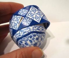 a hand holding a blue and white ceramic object