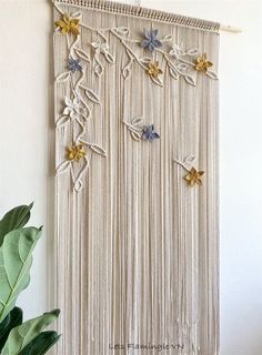 a wall hanging with flowers on it next to a potted plant