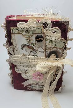 an altered book is decorated with lace and pearls on the edges, along with ribbon