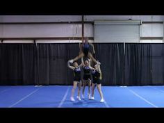 three girls in black and purple cheerleaders doing a handstand on a blue floor