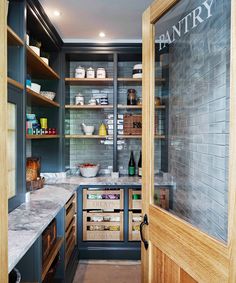 an open pantry with lots of food and drinks on shelves next to a door that leads to the kitchen