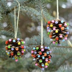 two pine cones hanging from a tree with colored beads on them and one is made out of wood