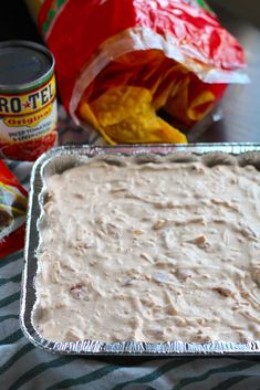 a pan filled with food sitting on top of a table next to chips and salsa