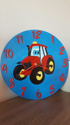 a blue clock with a red tractor on it's face and numbers painted on the front