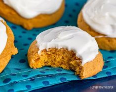 several pumpkin cookies with white frosting on a blue cloth