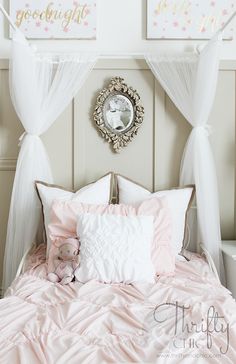 a bed with pink and white comforters, pillows and a clock on the wall