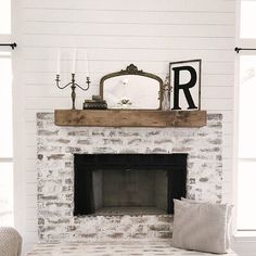 a living room with a white brick fireplace and wooden mantel above the fire place