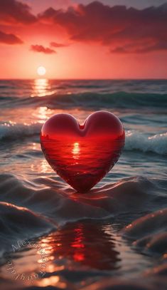 a heart shaped object floating in the ocean at sunset