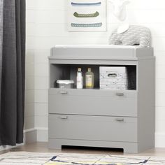 a baby changing table with two drawers and bottles on the bottom shelf next to it