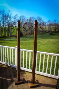 two wooden poles standing on top of a deck next to a lush green field with trees