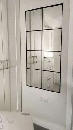 an empty room with white walls and cabinets in the corner, including a mirror on the wall