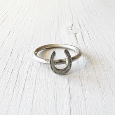 Featured here are three simplistic sterling silver lucky horseshoe rings. The horseshoes were part of a vintage charm.  These rustic and unique rings would make a lovely gift, or a fantastic addition to any jewelry collection.  Vintage Item Stamps/hallmarks- Unmarked but created from a vintage sterling silver charm (acid tested) and 925 sterling silver gauge wire for the shank.  There are 3 rings currently available: US size 5 3/4 US size 6 US size 6 These rings are sizeable within reason by your local jeweller. The face of the ring measures approximately (horseshoe) 9 mm x 7 mm. The shank measures 2 mm wide.    Condition- These rings are in very good pre owned condition with only minor signs of age and wear.  These pieces were converted from charms to rings by a professional silversmith a Silver Adjustable Horseshoe Rings, Classic Sterling Silver Horseshoe Jewelry, Classic Horseshoe-shaped Sterling Silver Jewelry, Silver Horseshoe Ring As Gift, Silver Horseshoe Ring For Gift, Horseshoe Rings, Vintage Ring Box, Horseshoe Ring, Vintage Sterling Silver Charms