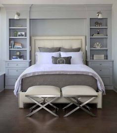 a bedroom with a bed, two chairs and shelves on the wall next to it