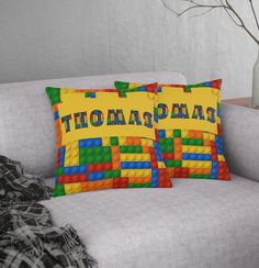 two pillows on a couch with the word barcelona spelled in legos across each pillow