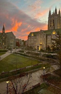 the sun is setting in front of a large building with many spires and windows