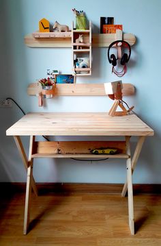 a wooden desk sitting on top of a hard wood floor next to a blue wall