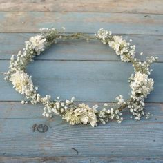 a wreath made out of dried flowers sitting on top of a wooden floor next to a wall