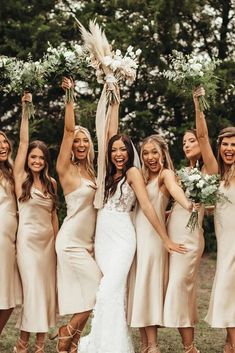 a group of women standing next to each other holding bouquets in their hands and posing for the camera