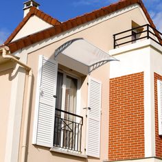 an orange brick building with white shutters and a balcony