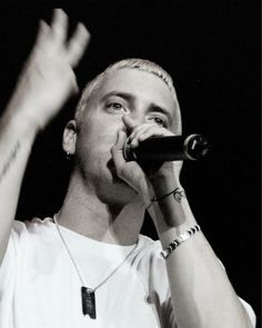 a male in a white shirt is singing into a microphone