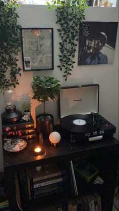 a record player sitting on top of a wooden table next to a potted plant