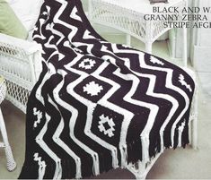 a black and white afghan sitting on top of a bed next to a wicker chair