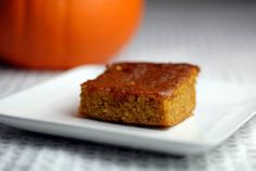 a piece of cake sitting on top of a white plate next to an orange pumpkin