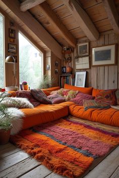 an orange couch sitting in the middle of a living room next to a large window