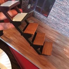 a person is holding a knife over some wooden blocks on a table with plates and cups