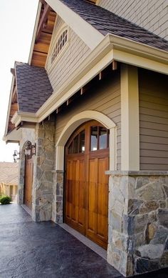 an image of a house with stone and wood accents on the front door, along with two garage doors