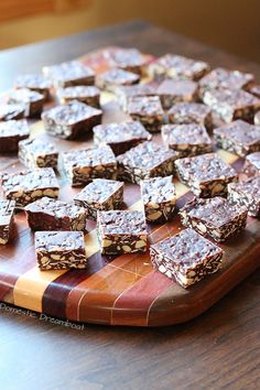 a wooden cutting board topped with lots of pieces of chocolate and granola bars on top of it