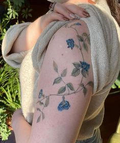 a woman with a flower tattoo on her arm and shoulder is posing for the camera