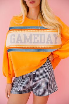 Take your gameday look up a notch with our GAMEDAY ORANGE PULLOVER. Made with a vibrant orange crop design and accented with a blue, gold, and white striped ribbon featuring a playful blue Gameday design. It's the perfect way to show off your team spirit with style. Go team! All orders are currently shipping within 14 business days. To receive item quicker, expedited shipping is available at checkout. Gameday Sweatshirt, Cotton Sweatshirt With Graphic Print For Game Day, Orange Tops For Game Day With School Spirit, Retro Game Day Sweatshirt With Letter Print, Sporty Orange Tops For Game Day, Collegiate Game Day Top With Custom Print, Gameday Outfit Alabama, Collegiate Orange Tops For Game Day, Striped Ribbon