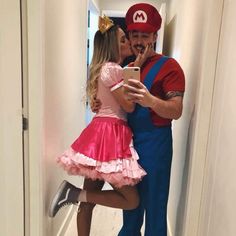 a man and woman dressed up as mario and princess peaches kissing on the cheek