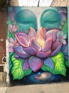 a mural on the side of a building with a buddha face and flowers painted on it