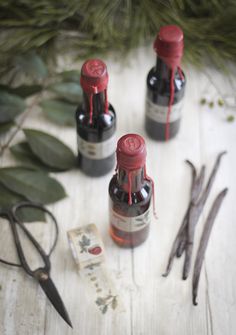 three bottles with red caps sitting on top of a table next to scissors and other items