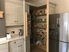 an open pantry in the middle of a kitchen with stainless steel appliances and white cabinets