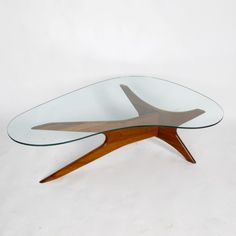 an oval glass table with wooden legs on a white background in the shape of a plane