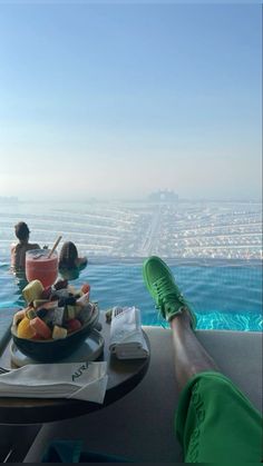 two people sitting at a table with food and drinks in front of an ocean view